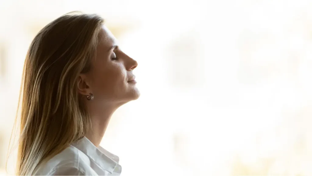 Ženska z zaprtimi očmi, ki mirno diha in simbolizira notranji mir ter mentalno zdravje