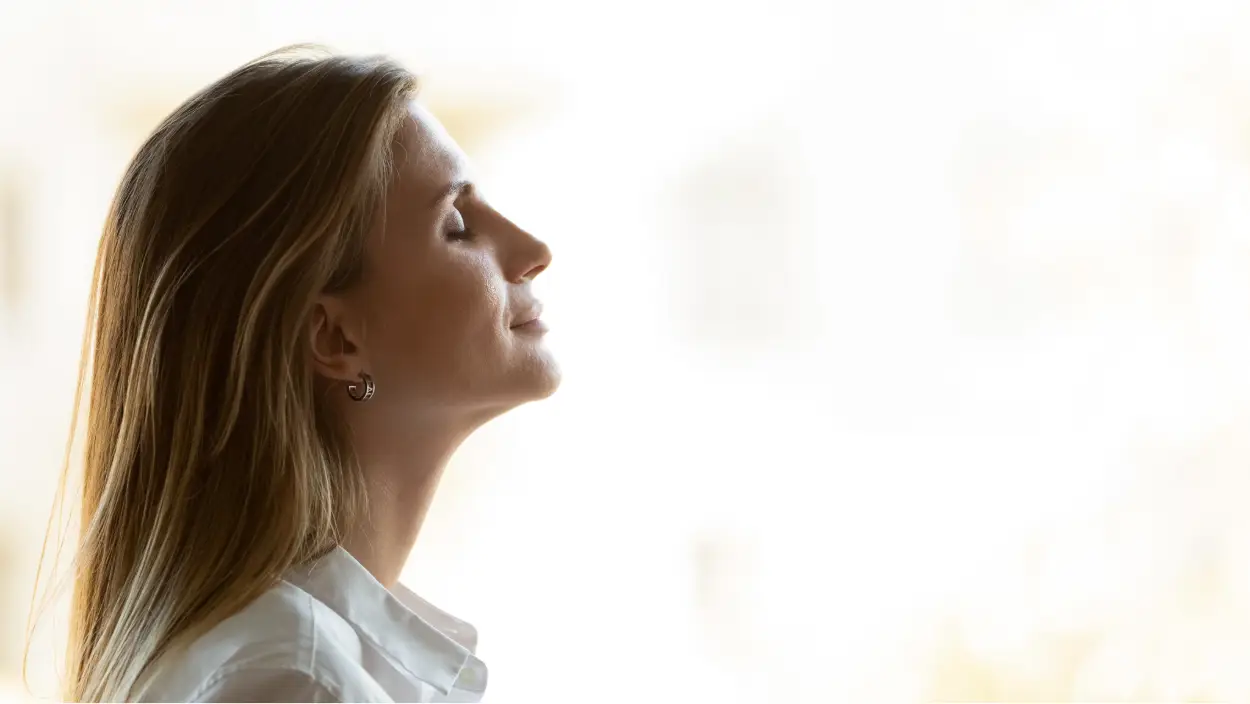 Ženska z zaprtimi očmi, ki mirno diha in simbolizira notranji mir ter mentalno zdravje